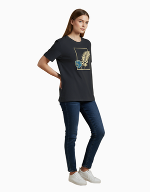 Woman wearing a black t-shirt with a gold and blue design, paired with blue jeans and white sneakers on a white background